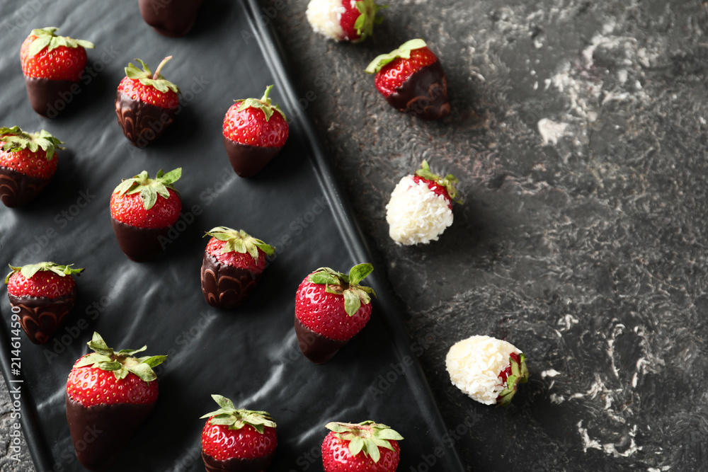 Fototapeta premium Plate with delicious strawberry covered with chocolate on grey textured background