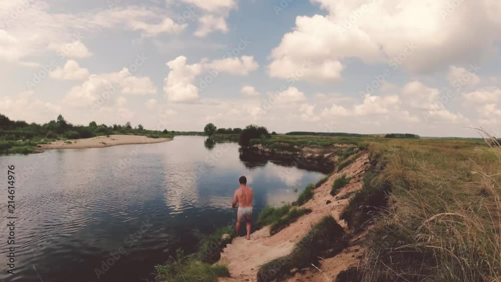 the fisherman is fishing on the river by spinning. the fisherman is fishing on the river by spinning.