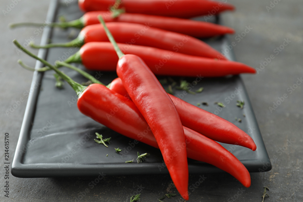 Plate with fresh chili peppers on grey background, closeup