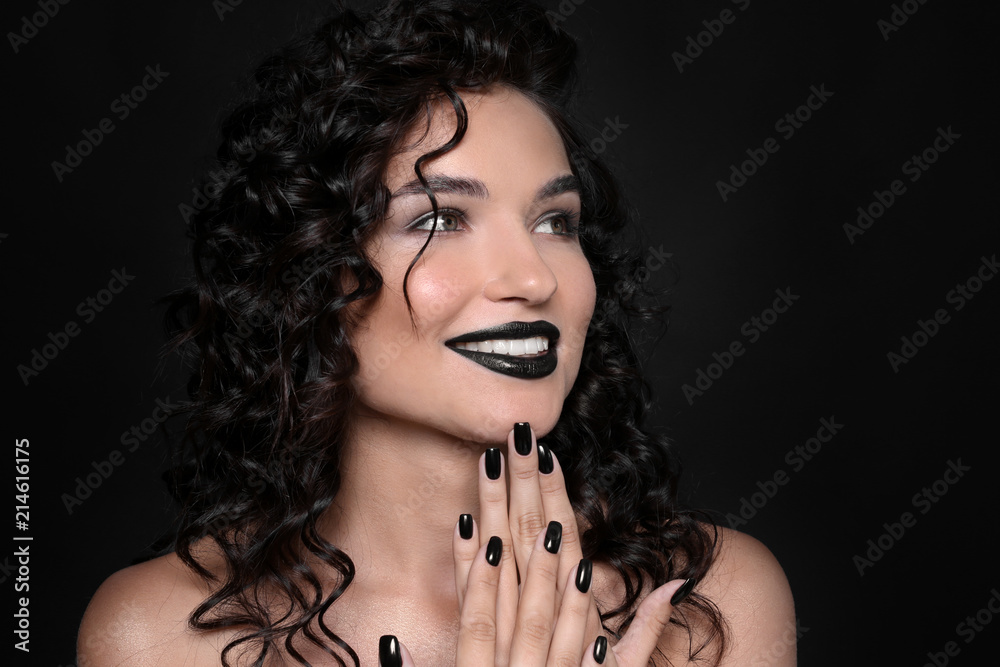 Obraz premium Fashionable young woman with black manicure on dark background