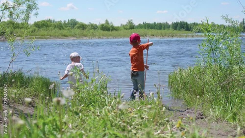 Two children catch fish on the river Bank. Beautiful summer landscape. Outdoor recreation. photo