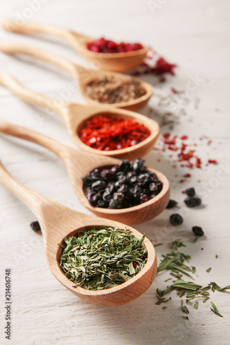 Spoons with different dry spices on wooden background