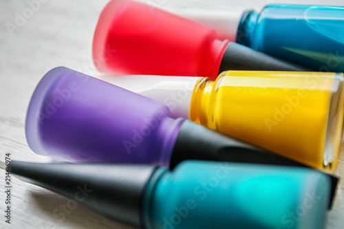 Bottles of colorful nail polishes on wooden background, closeup