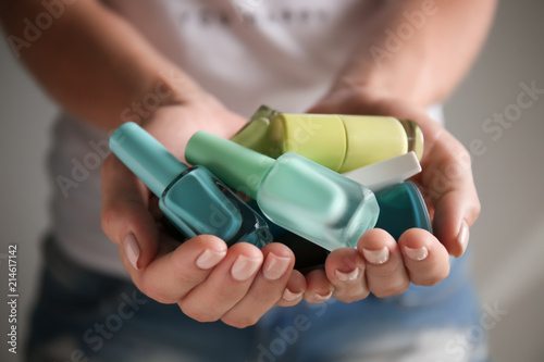 Woman holding bottles of colorful nail polishes, closeup