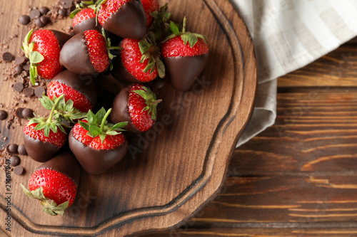 Board with tasty chocolate dipped strawberries on wooden table
