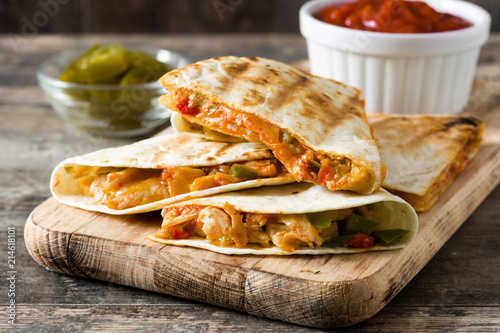 Mexican quesadilla with chicken, cheese and peppers on wooden table. 