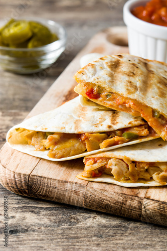 Mexican quesadilla with chicken, cheese and peppers on wooden table. 