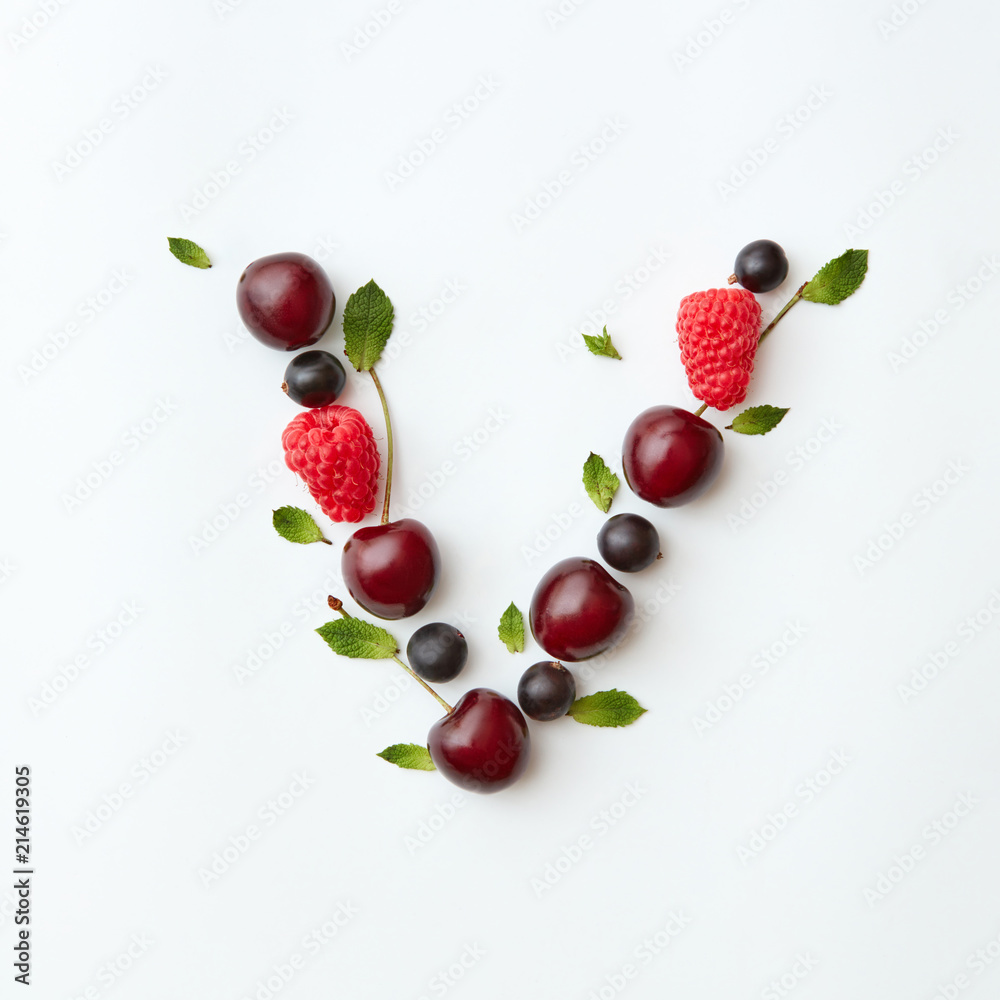 Berries organic pattern of letter V english alphabet from natural ripe berries - black currant, cherries, raspberry, mint leaf isolated on a white background. Berries organic pattern of letter V english alphabet from natural ripe berries - black currant, cherries, raspberry, mint leaf isolated on a white background.