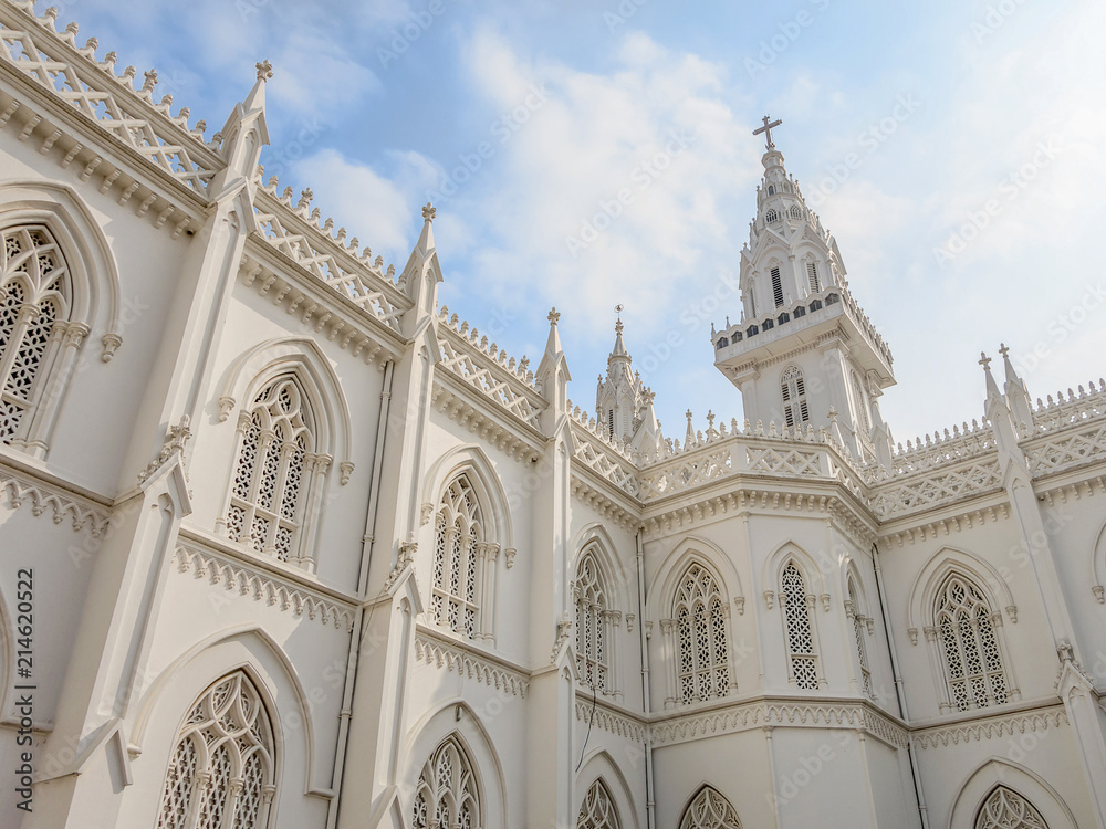 The upper part of the Lourdes Cathedral of white color on the background with the blue sky. View of the Gothic style building in South India, Trichur