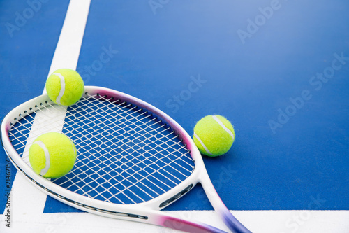 Tennis ball and tennis racket on a tennis court. Close up of tennis ball and tennis racket on hard court. © Sirichai