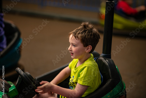 Happy young boy rides electric bumper car amusement ride on shore boardwalk