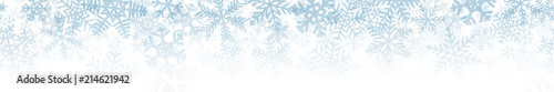 Christmas horizontal seamless banner or background of many layers of snowflakes of different shapes, sizes and transparency. Gradient from light blue to white