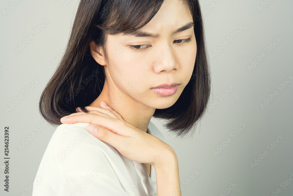 Asian girl in white casual dress catch that shoulder, Because of the pain of hard work. Or something hit the shoulder. on a gray background gives a soft light. Asian girl in white casual dress catch that shoulder, Because of the pain of hard work. Or something hit the shoulder. on a gray background gives a soft light.