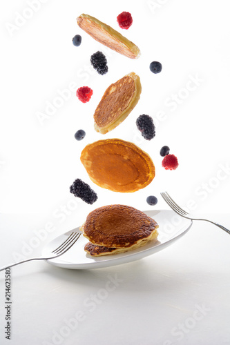 Flying stack of pancakes with blueberry, blackberry and raspberry isolated on white background