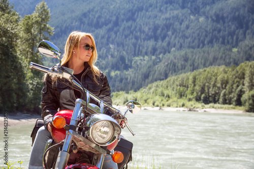 Young woman on a motorcycle in nature during a vibrant sunny summer day. Taken in Squamish, North of Vancouver, British Columbia, Canada.