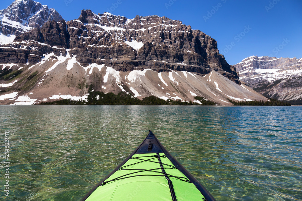 Kayaking in a glacier lake during a vibrant sunny summer day. Taken in Bow Lake, Banff National Park, Alberta, Canada.