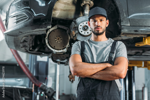 confident mechanic posing with crossed arms in auto repair shop