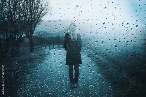 Back view of lonely sad woman standing outdoor with artistic rain drops background. photo