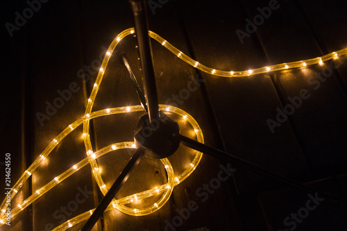 Background wallpaper of yellow light led strip passing through stands and drums on a wood music concert stage.