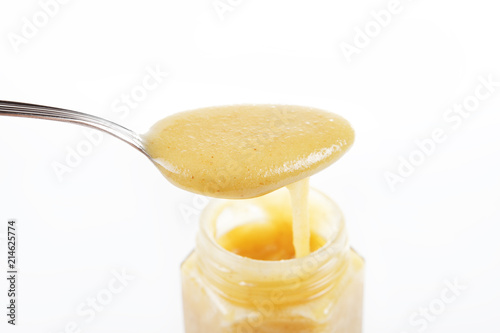 Jar of sweet honey with silver spoon on a white background. Health and beauty concept.