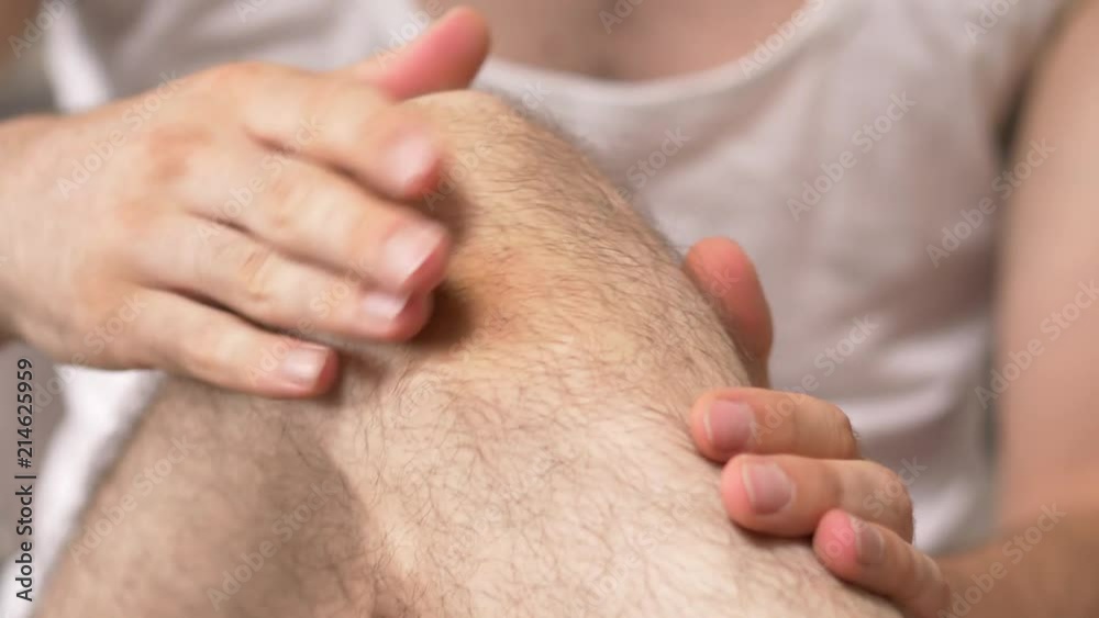 Man feeling pain in the knee area and massaging it with his hands to relief the pain. Man feeling pain in the knee area and massaging it with his hands to relief the pain.