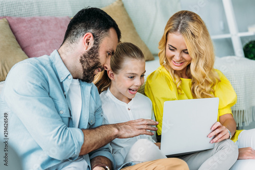 smiling young family using laptop together at home © LIGHTFIELD STUDIOS
