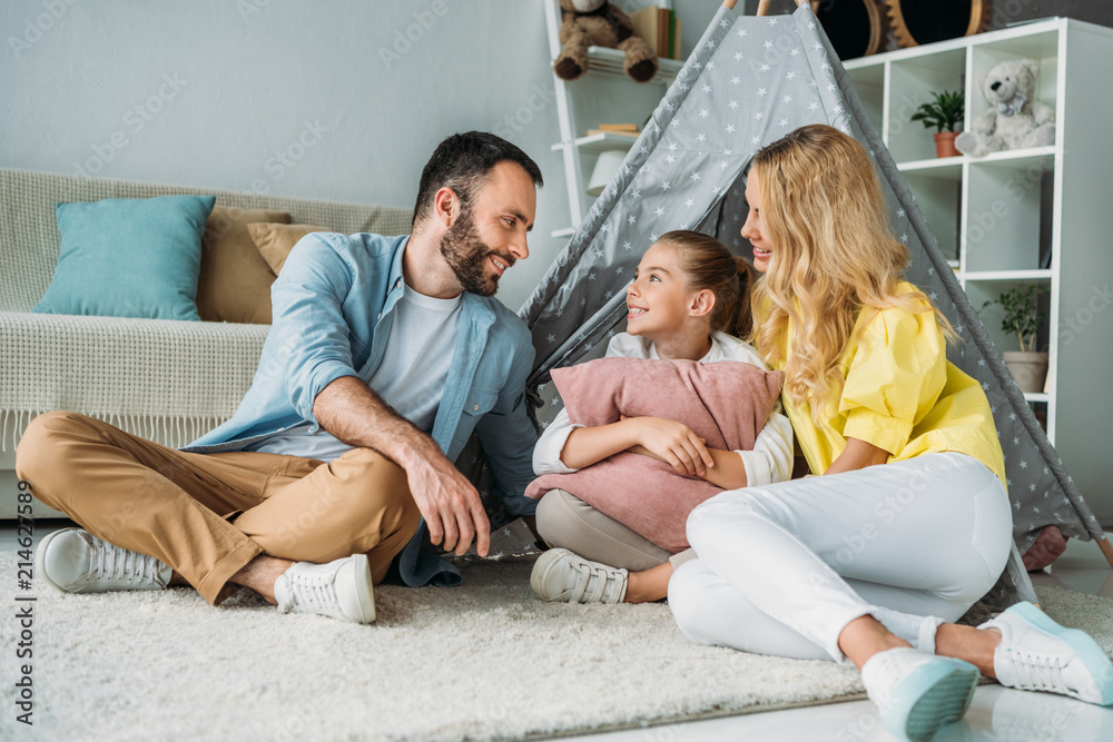 happy young family sitting on floor with teepee happy young family sitting on floor with teepee
