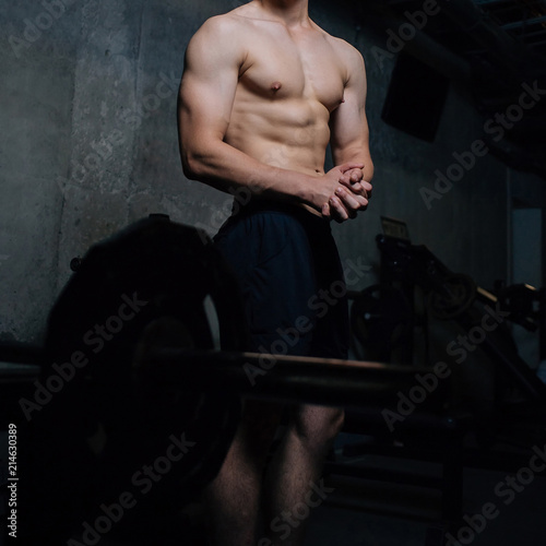 Closeup of a handsome power athletic man bodybuilder doing exercises with dumbbell. Handsome man doing biceps lifting in a gym.Dark background. Unrecognizable, no face portrait