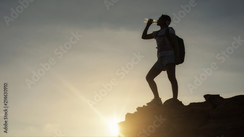 Silhouette woman drink water at mountain peak