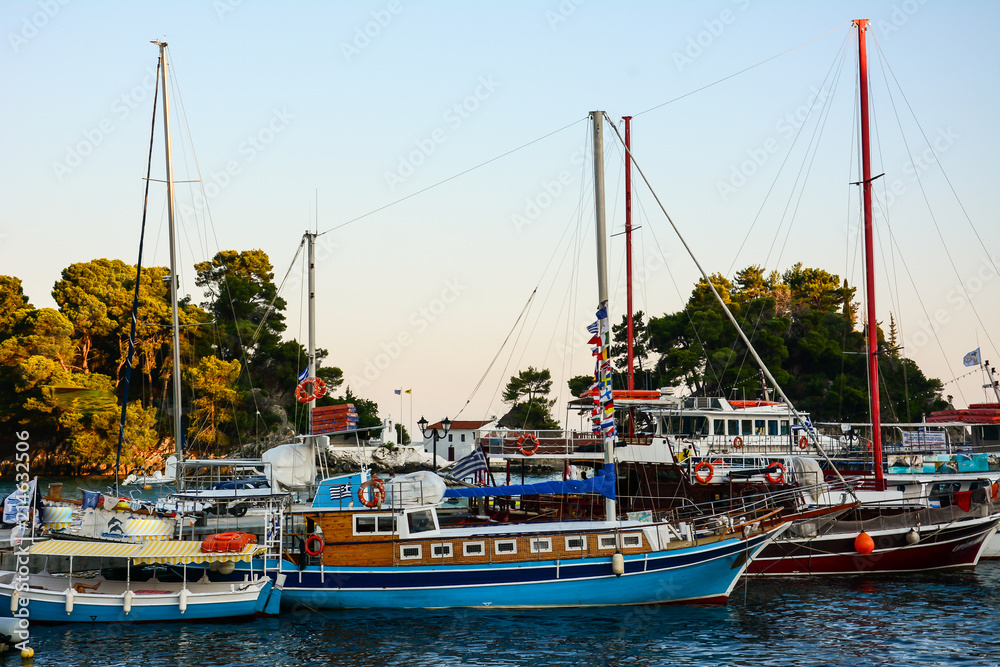 Colorful wooden tourist boats anchored in the beautiful Greek port are waiting for the cheerful tourists for the next day. A beautiful arc with turquoise blue sea and a hospitable atmosphere.