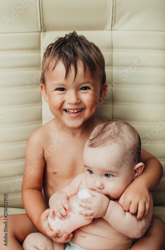 brother feeding little sister with milk or cereal with a bottle photo