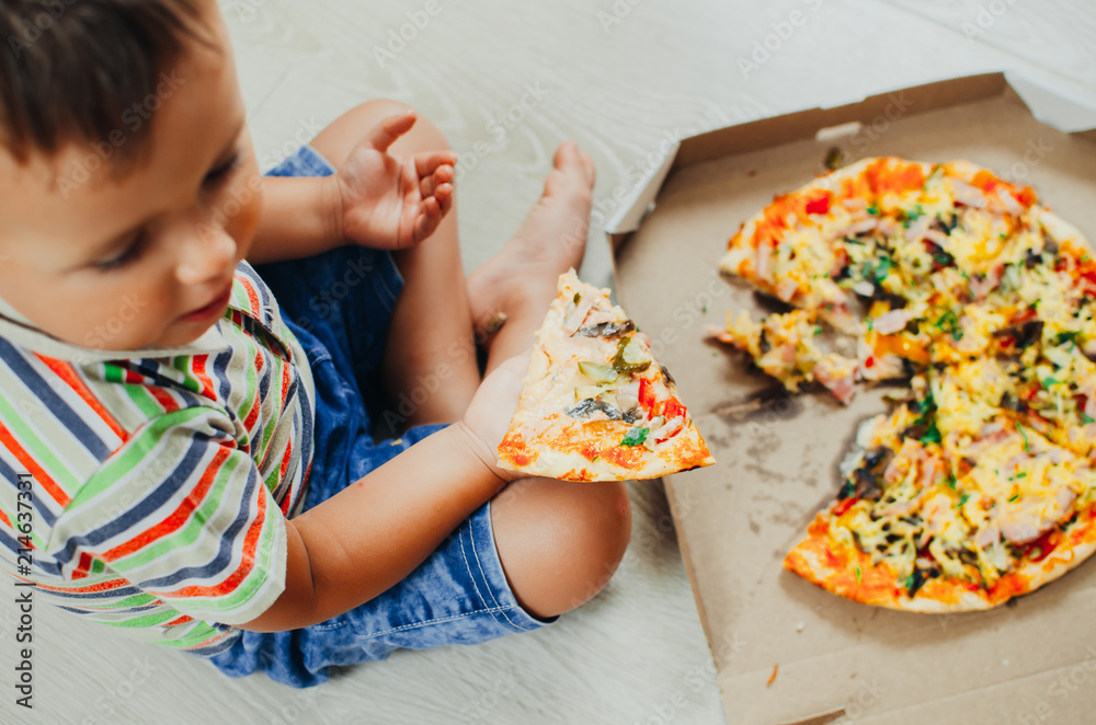 charming boy sitting on the floor eating pizza charming boy sitting on the floor eating pizza