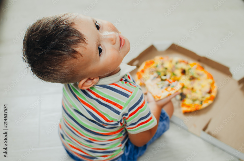 charming boy sitting on the floor eating pizza charming boy sitting on the floor eating pizza