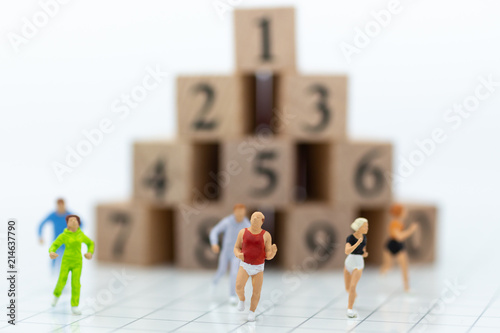 Miniature people running to stack of number wooden block . Image use for healthy , exercise concept.