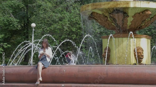 Girl reading a book near the fountain. Timelapse