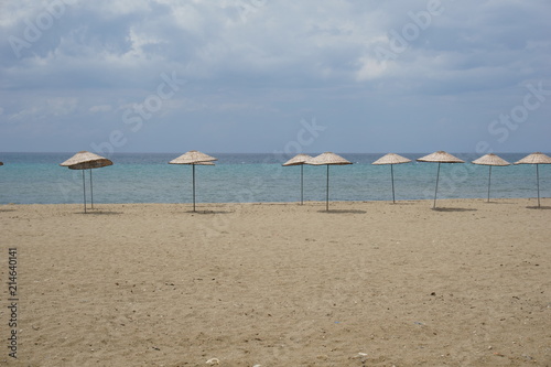 Thatched parasols in an empty beach at sunny day