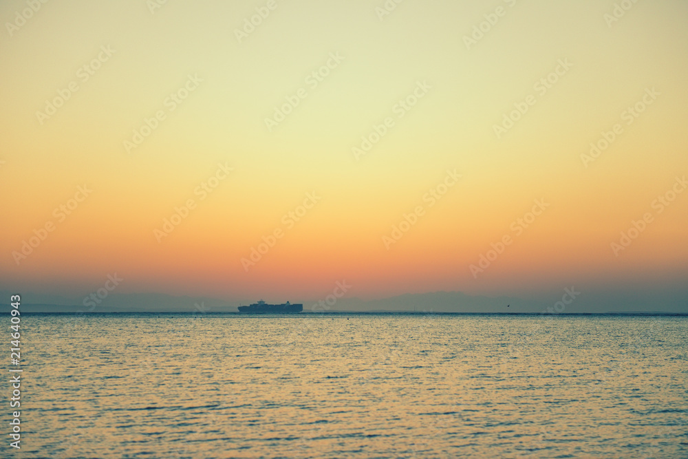 cargo ship on horizon at sea sunrise