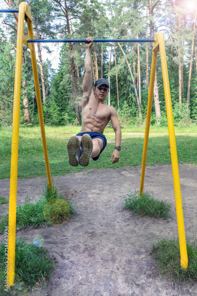A young man is engaged on a horizontal bar in the park