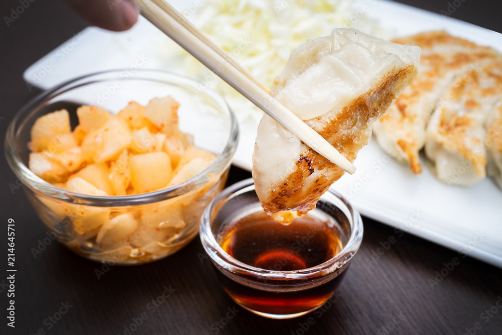 hand with chopsticks holding a piece of gyoza fried - dumplings snack , with soy sauce hand with chopsticks holding a piece of gyoza fried - dumplings snack , with soy sauce