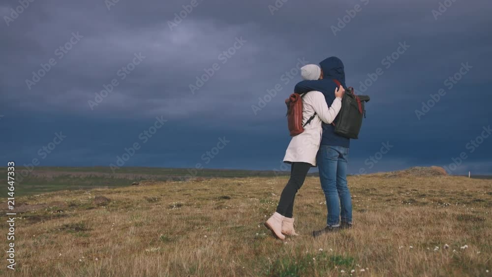 Young loving couple hugging in field on background of epic dramatic clouds, slow motion Young loving couple hugging in field on background of epic dramatic clouds, slow motion