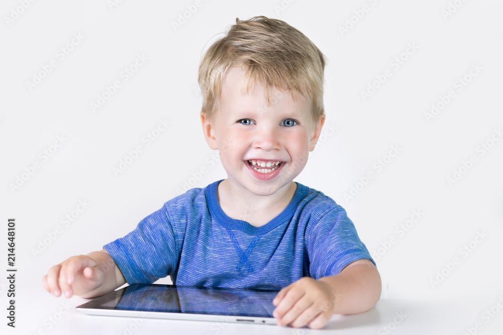 Three years old little kid boy playing children educational or developing games or on the tablet computer at home on white background Three years old little kid boy playing children educational or developing games or on the tablet computer at home on white background