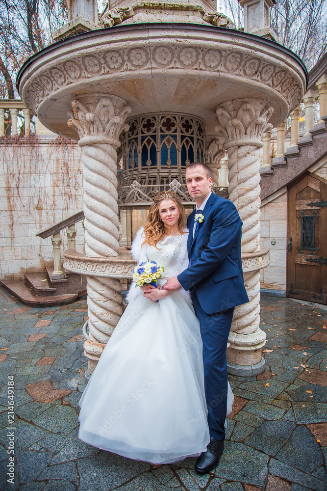 Groom and charming bride together on background of creative fountain, in autumn