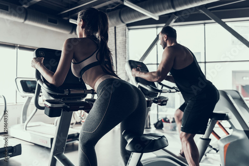 Woman an Man in Sportswear on Exercise Bike in Gym