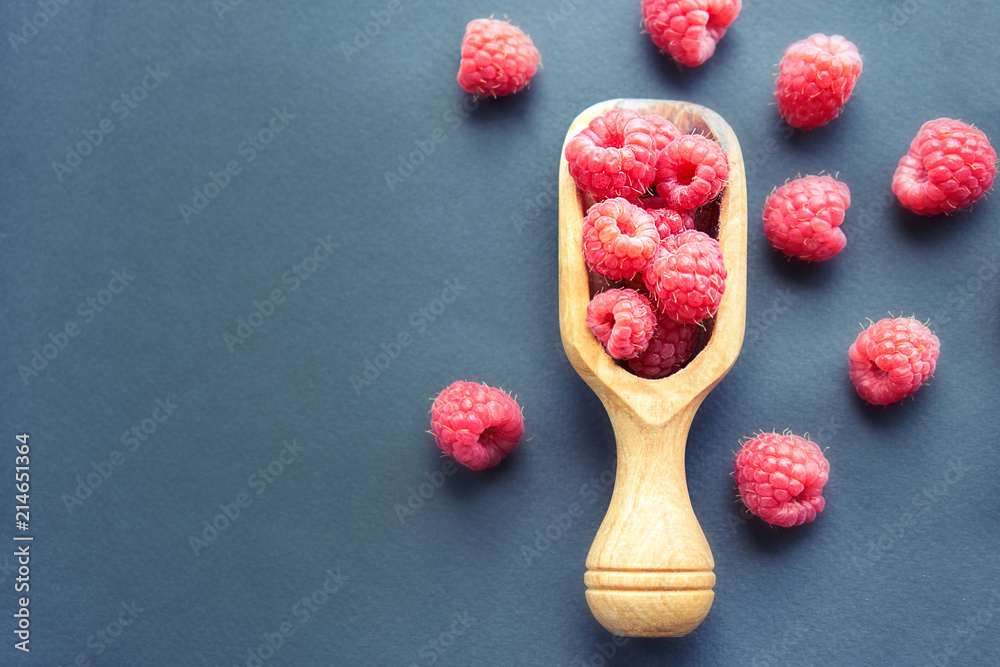 Fresh organic raspberries on black background. berries on a wooden spoon Fresh organic raspberries on black background. berries on a wooden spoon