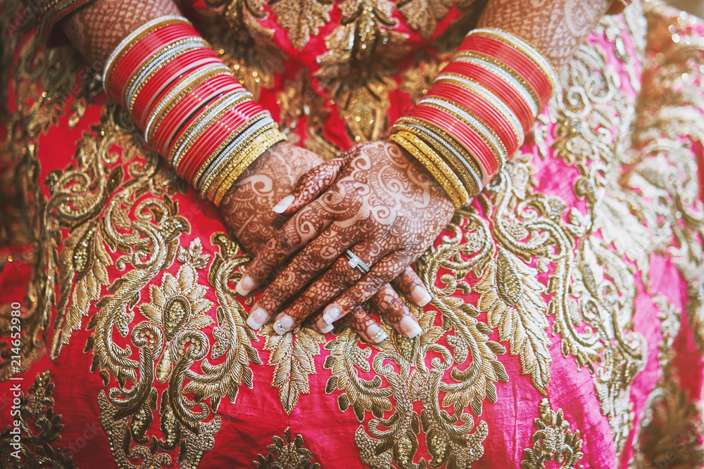 The hands of Indian bride with menhdi (henna) tattoo and bunch of glitter bangles on her wrist, close-up