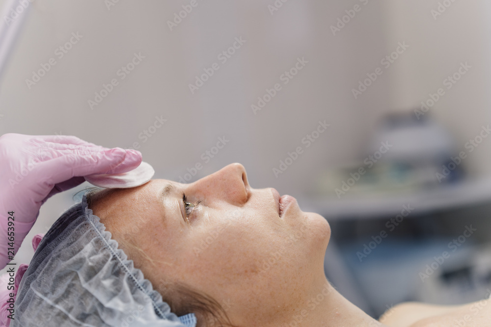 The hands of the cosmetologist on the face of the patient The hands of the cosmetologist on the face of the patient