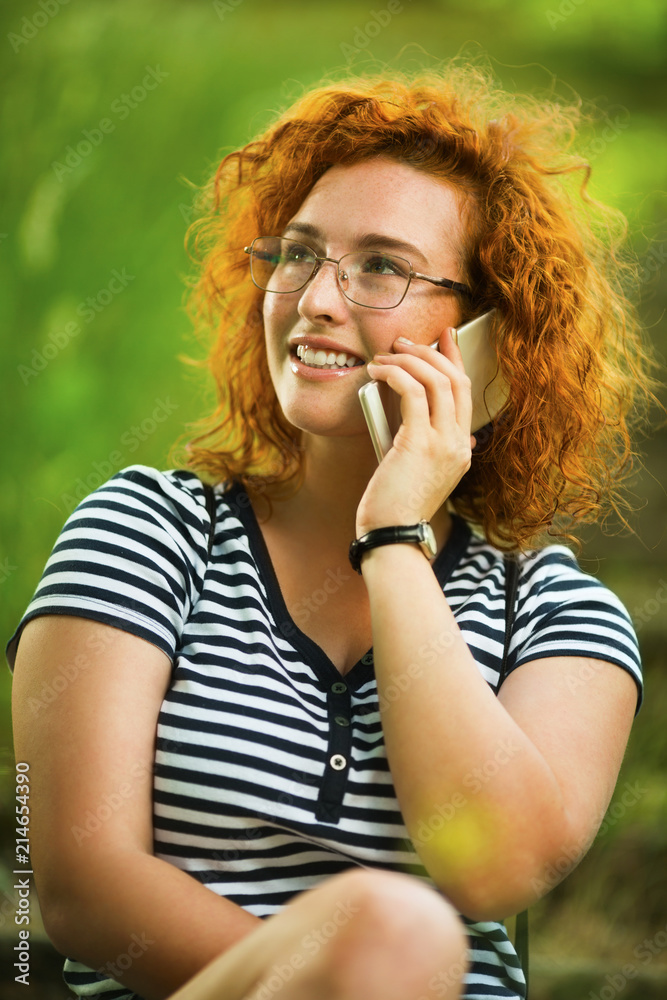 Young ginger woman using smartphone in park Young ginger woman using smartphone in park