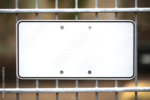 Leeres weißes Schild aus Metall an einem Zaun montiert