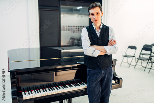 Photo Male pianist stands at the black grand piano