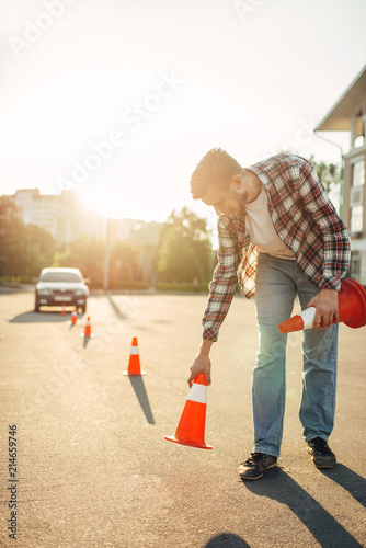 Instructor sets the cone, driving school concept